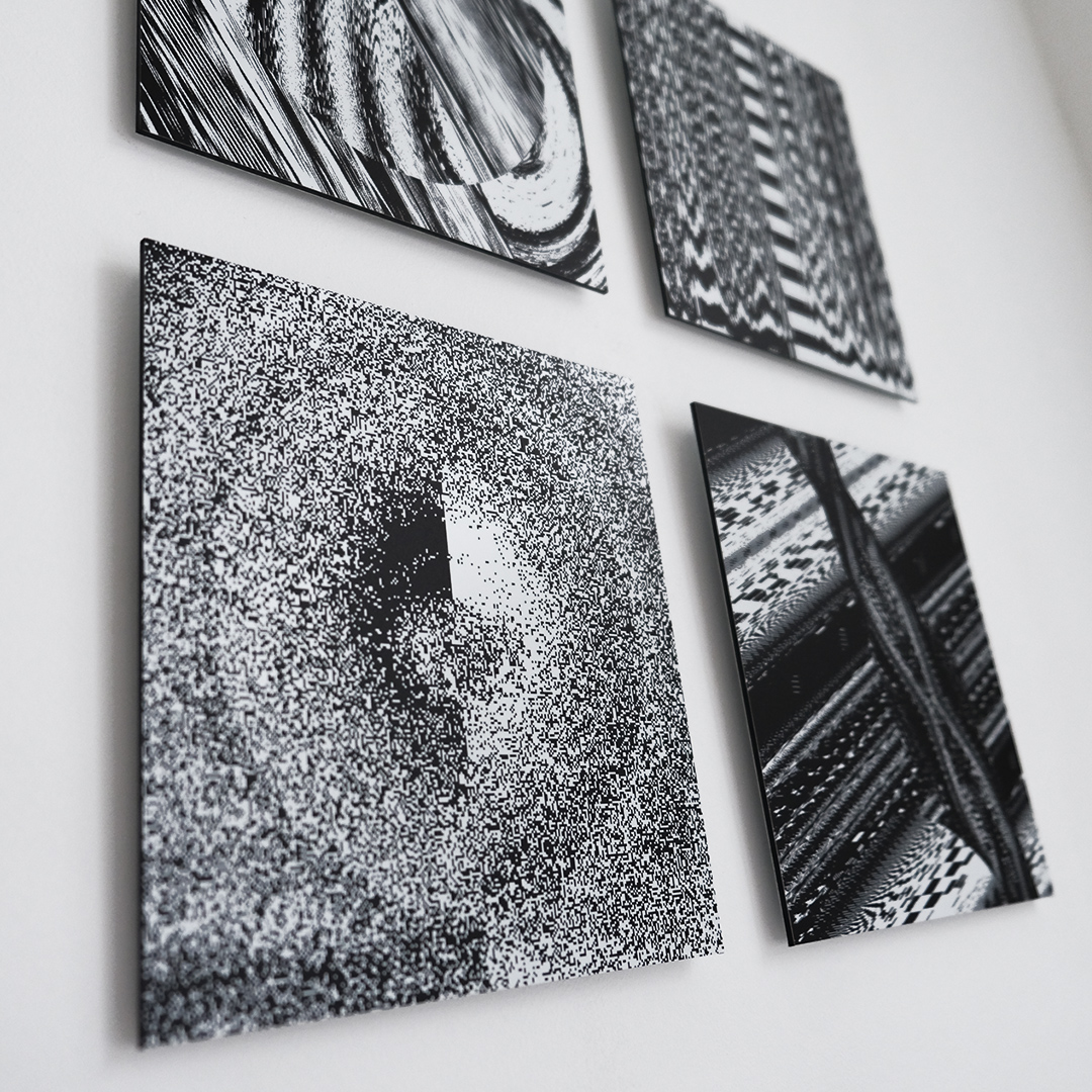 photograph of four 20x20cm abstract black & white prints hanging on a wall